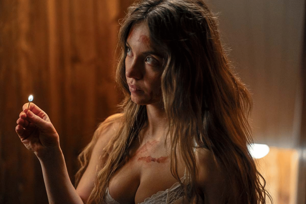 Woman with long wavy hair holds a lit match in a dimly lit room, with visible bruises and marks on her face and chest, wearing a white lace top.